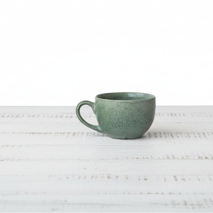 Green ceramic mug on a white textured surface