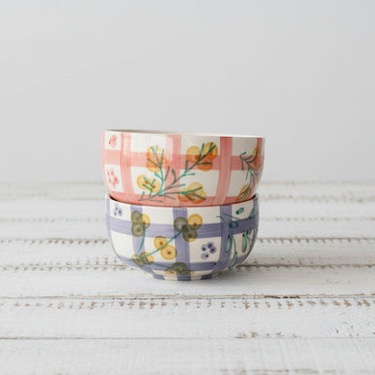 Two ceramic bowls with floral patterns stacked on a white wooden table