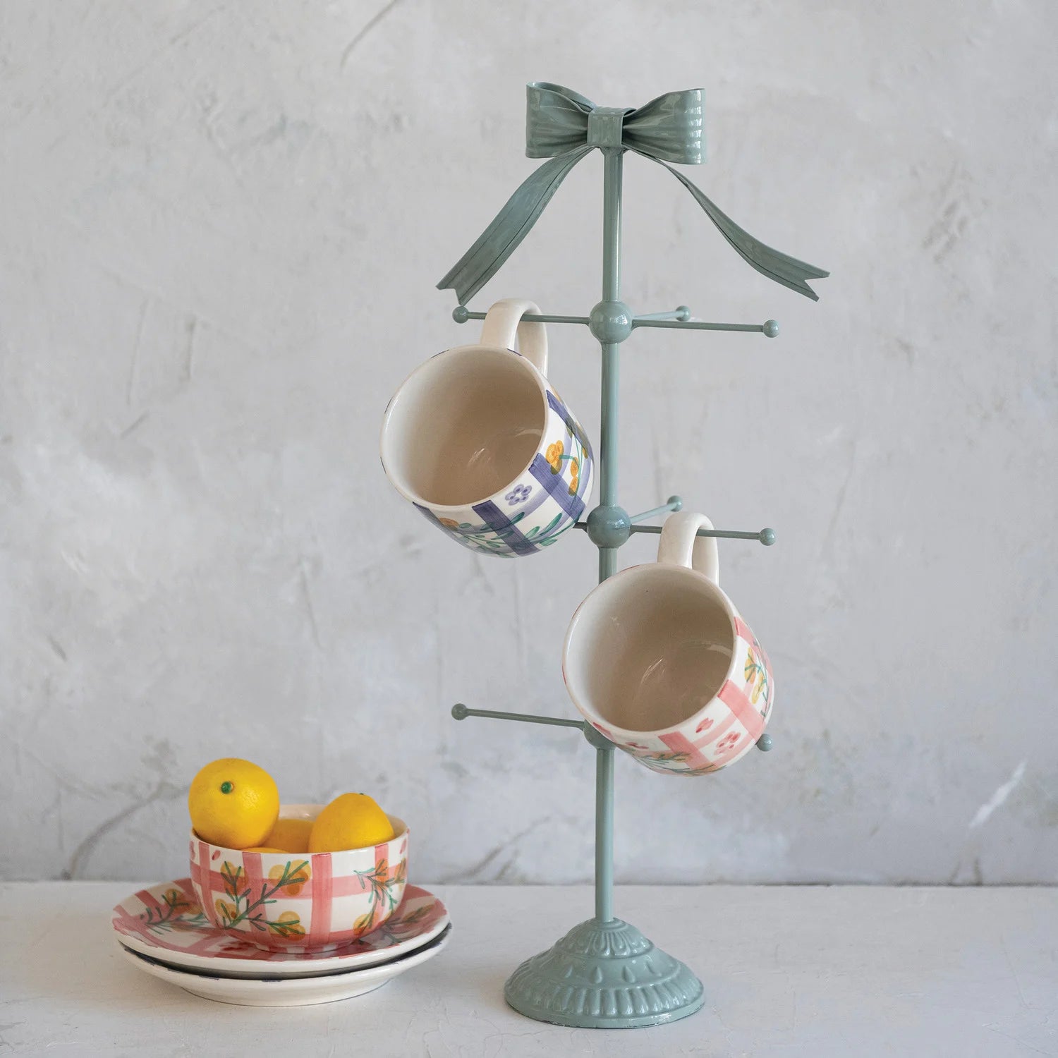 Teal mug tree with two decorated mugs on a light gray background
