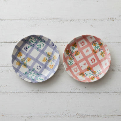 Two decorative plates with floral and plaid patterns on a white wooden background