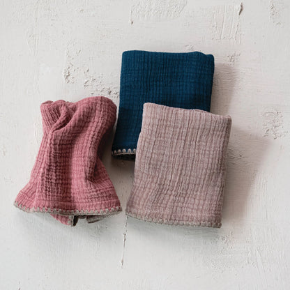 3 colors of kitchen towels draped on a beige surface