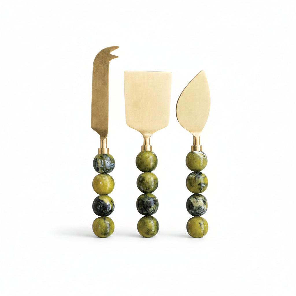 3 green handled cheese knives in a row on a white background