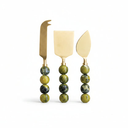 3 green handled cheese knives in a row on a white background