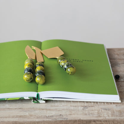 3 green handled cheese knives on an open book