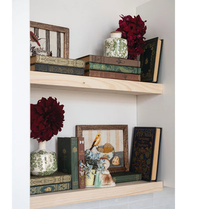 Decorative shelves with books, vases, and framed pictures on a white wall.