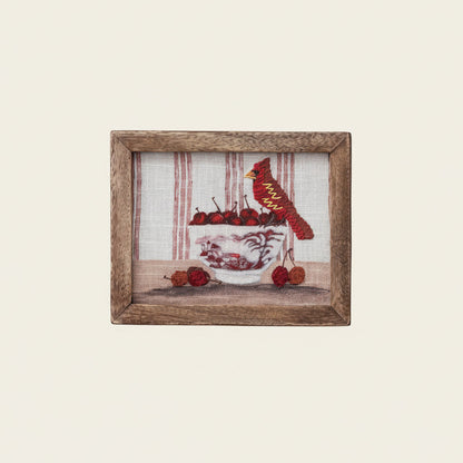 Framed artwork of a cardinal and cherries on a white background