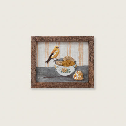 Framed artwork of a yellow bird perched on a bowl of lemons with yellow striped background