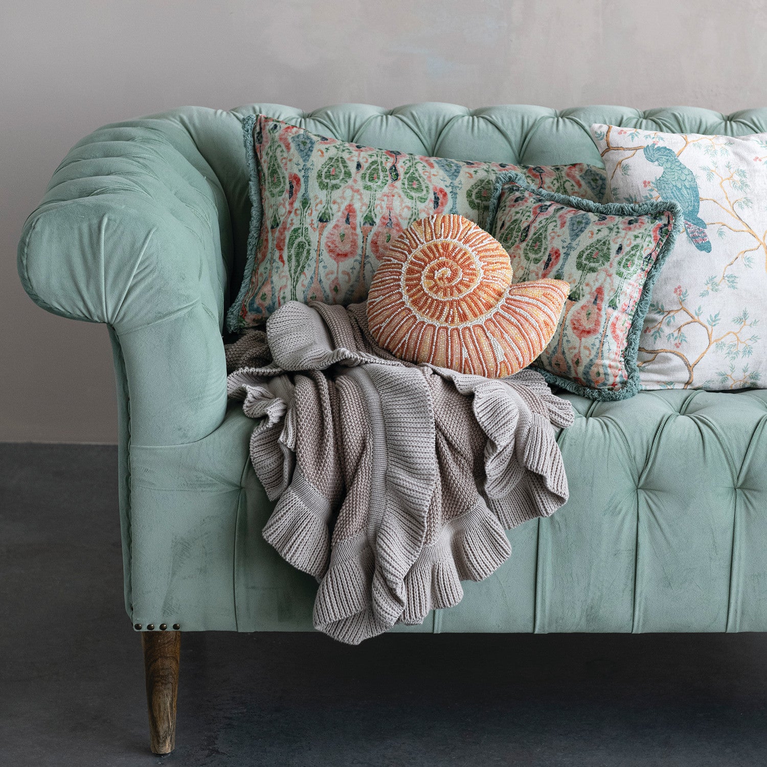 taupe cotton Knit Throw with Ruffle draped on a velvet couch
