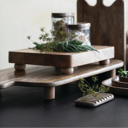Wooden cutting boards with jars and plants on a dark surface