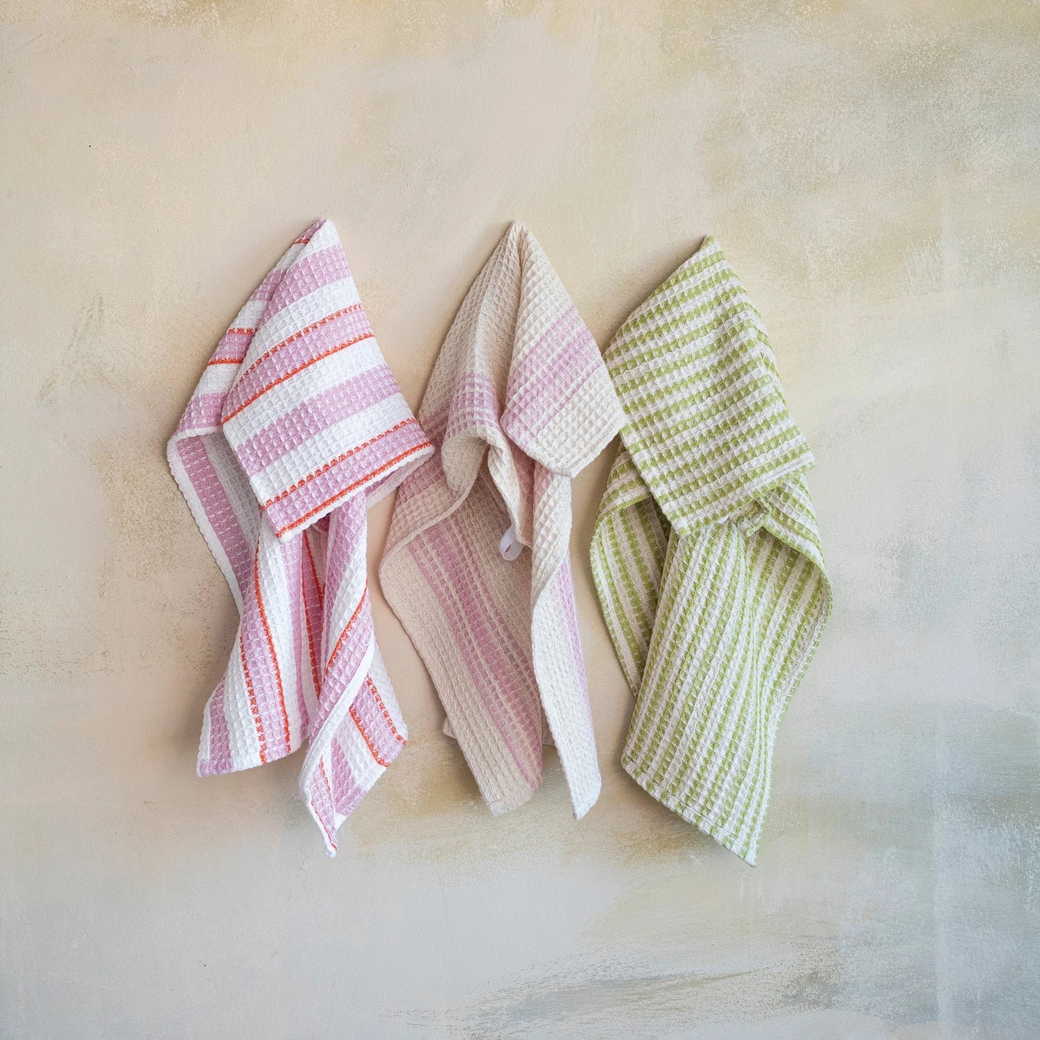 3 striped dishtowels draped on a beige background