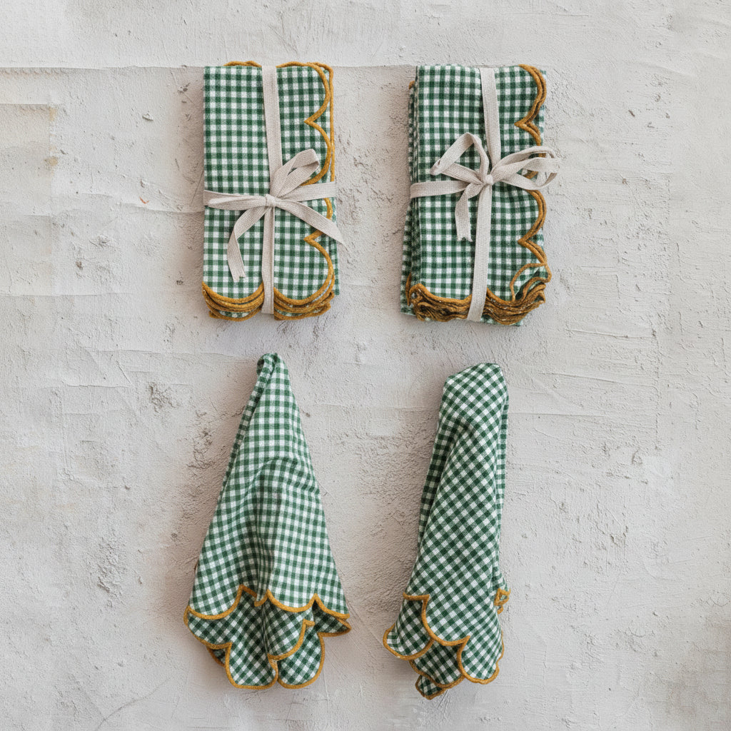 Two sets of green gingham napkins on a textured surface.