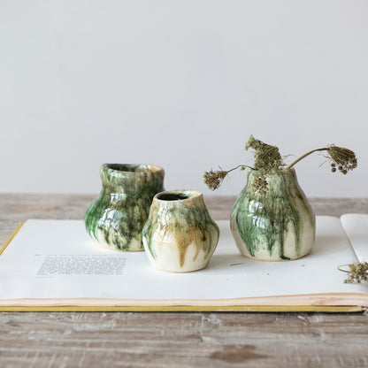 Three green ceramic vases on an open book with a minimal background
