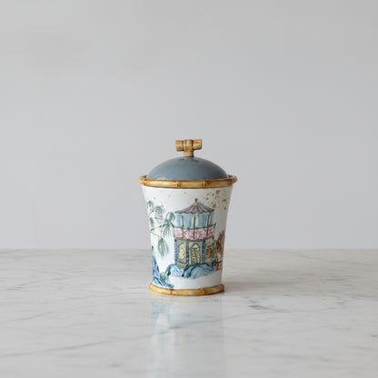 ceramic canister with pagoda style house and tree designs painted on it and bamboo-look trim details set on a marble countertop