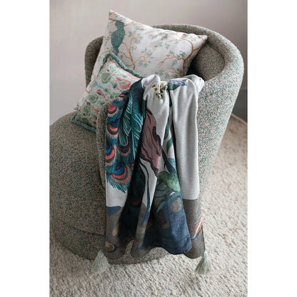 peacock throw blanket draped over an armchair with 2 decorative pillows on it