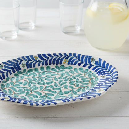 Decorative platter with blue and green pattern on a white surface with pitcher on lemonade