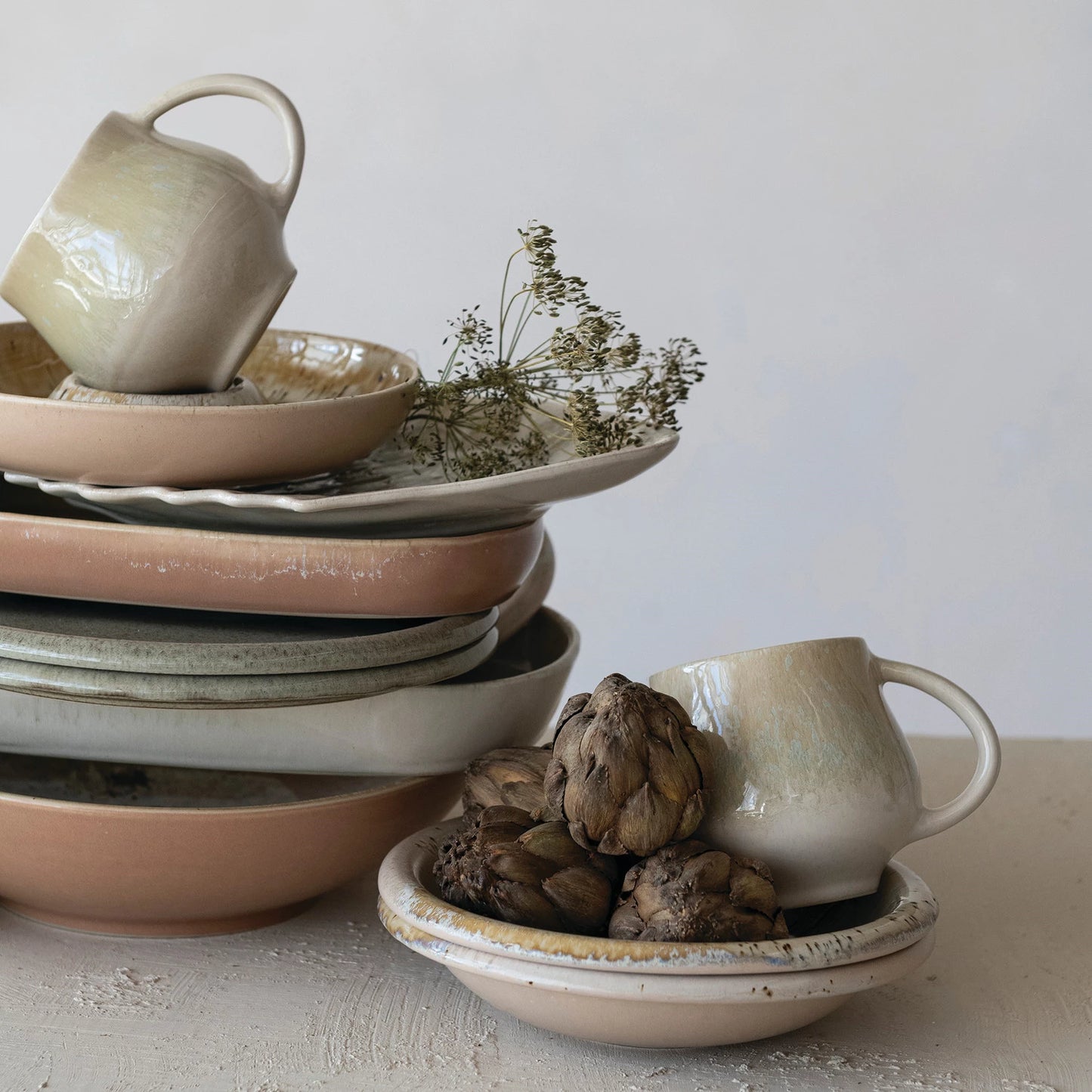 Stack of ceramic plates and platers  with natural elements on a light surface