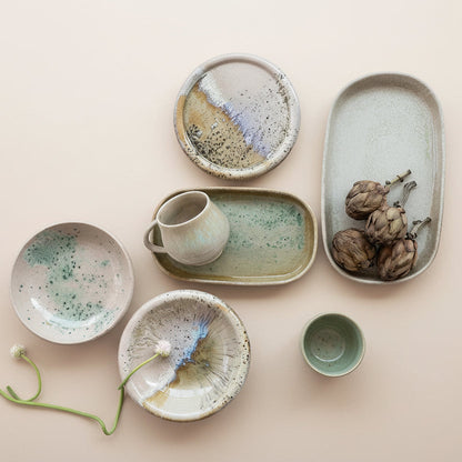 Collection of ceramic dishes and bowls on a beige background