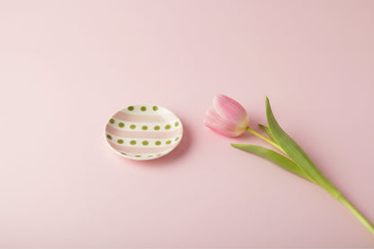 small round plate with pink stripes and green dots on a light pink background with a pink tulip