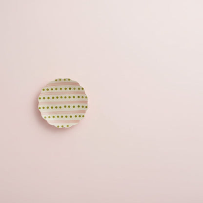 plate with pink stripes and green dots shown on pale pink background