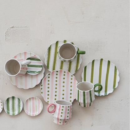 ceramic plates and mugs with pink and green striped and polka dot patterns on a plaster surface