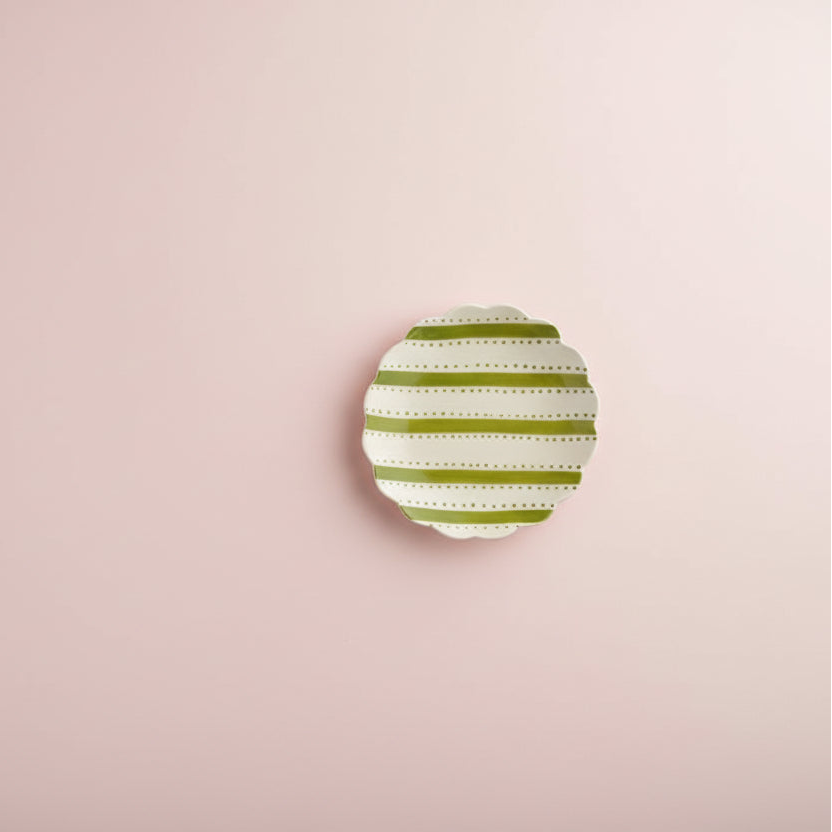 plate with green stripes and dots shown on pale pink background
