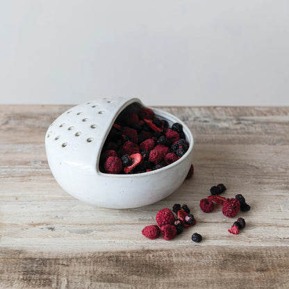 stoneware bowl strainer with berries in it on a wood surface
