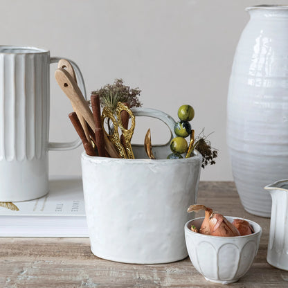 White ceramic container with kitchen utensils in it set on a wooden surface