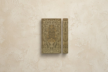 brown book cover and spine with scrolling gold design and titled "the days of auld lang syne" printed in the center of cover, shown on a beige plaster surface