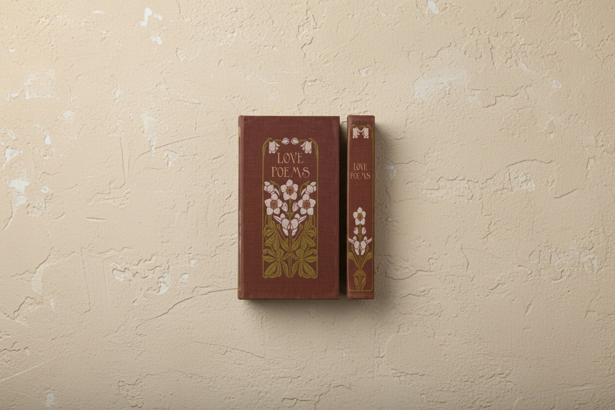 burgundy vintage style book with white floral design and titled " love poems" shown on a beige plaster surface