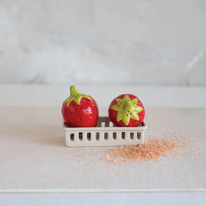 Strawberry shaped Salt & Pepper Shakers in white Basket set on a white wood surface with natural salt in a pile around it