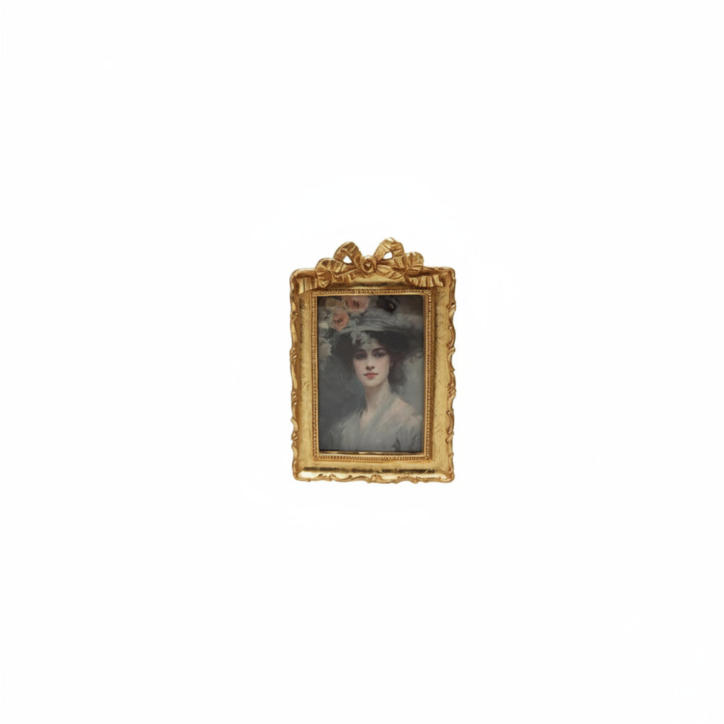 golden frame with bow on top and portrait of a woman in rectangular opening