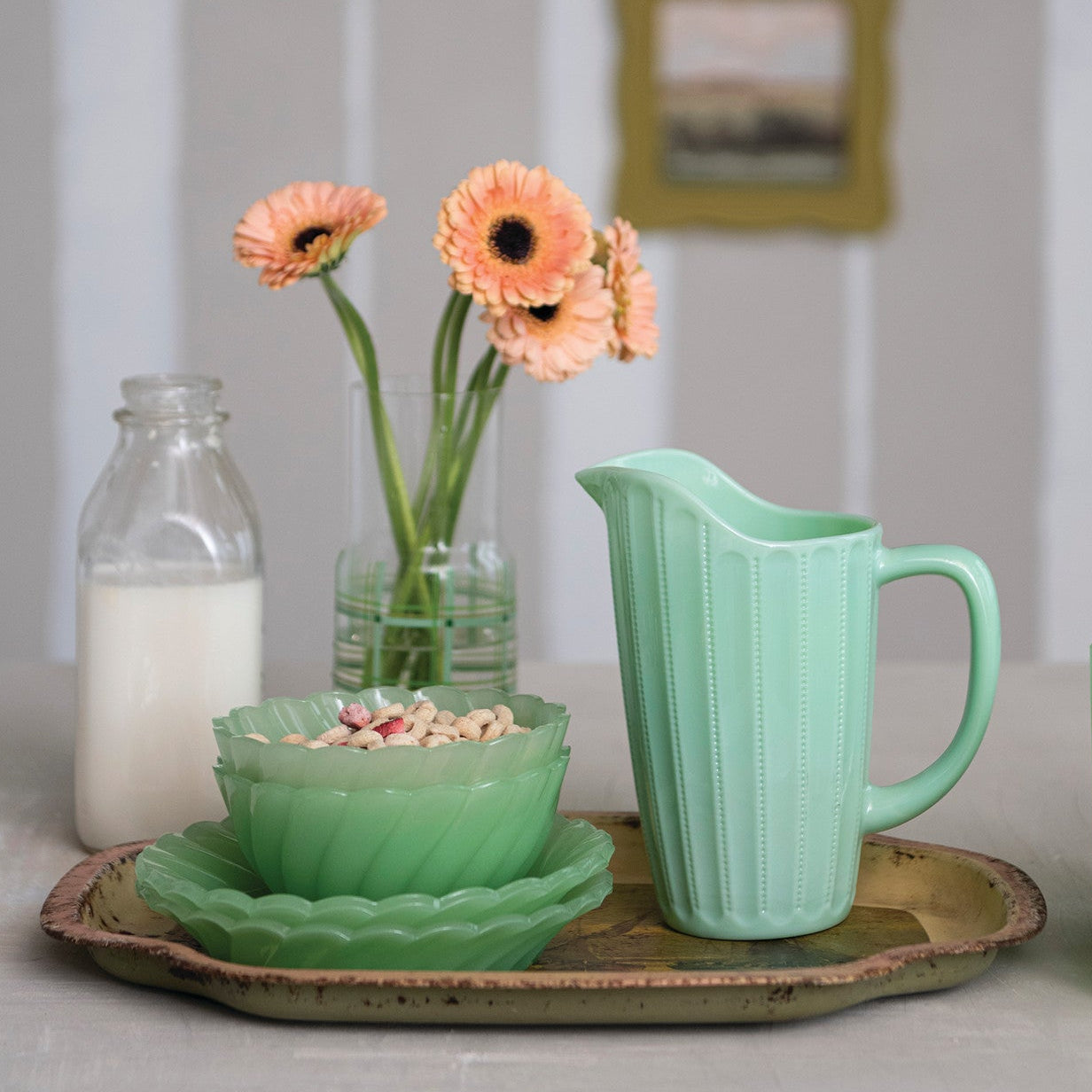 mint green pitcher arranged with dishes on a rustic tray with peach flowers in a glass vase against a softly blurred indoor background