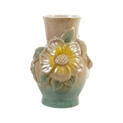 A vintage-style ceramic vase featuring a textured beige and green glaze, decorated with a large raised flower motif around the middle in yellow, white, and green tones, set against a plain white background.