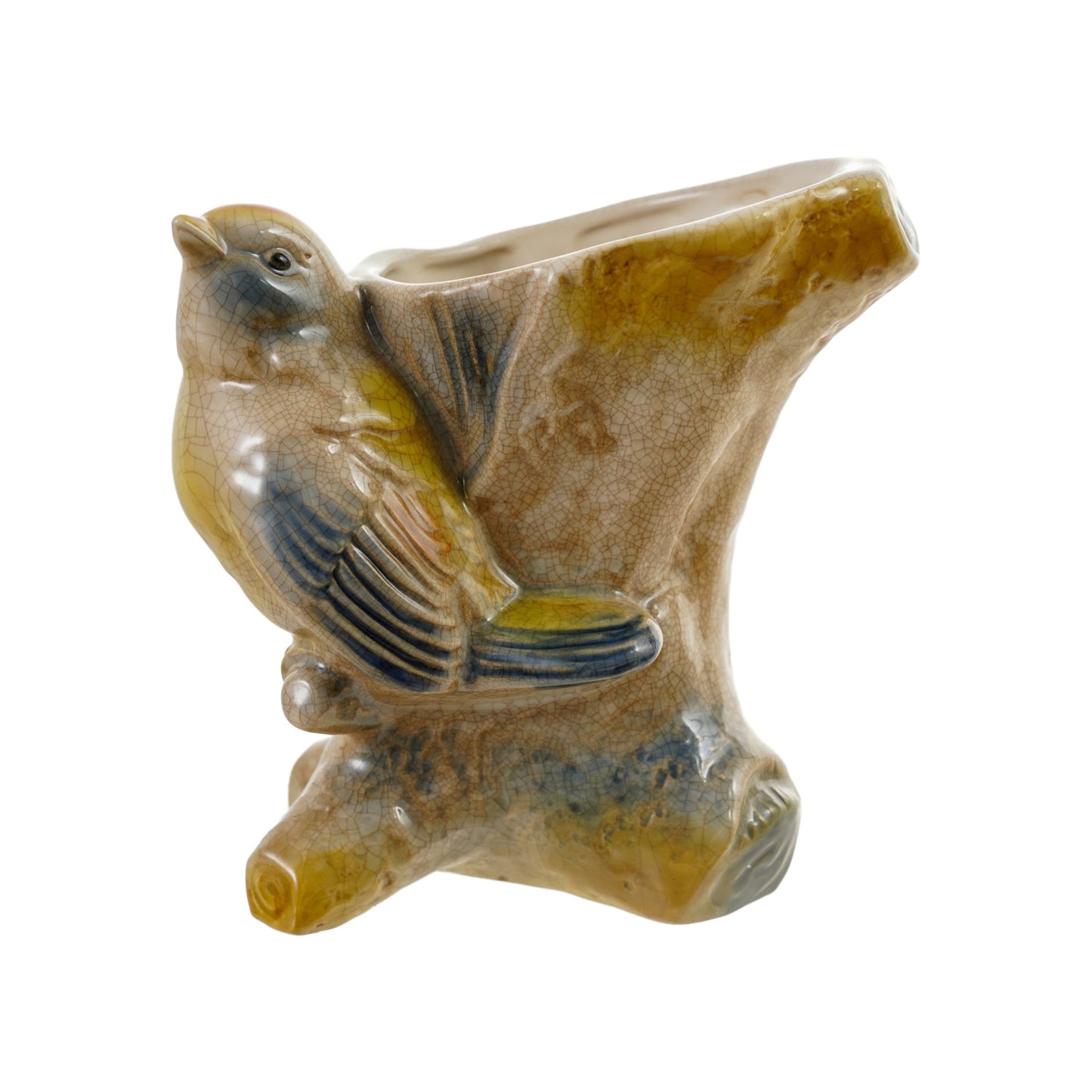 A ceramic bird figurine perched on a textured tree stump ceramic base, decorated with glossy glaze in earthy brown, yellow, and blue-gray tones, on a white background.