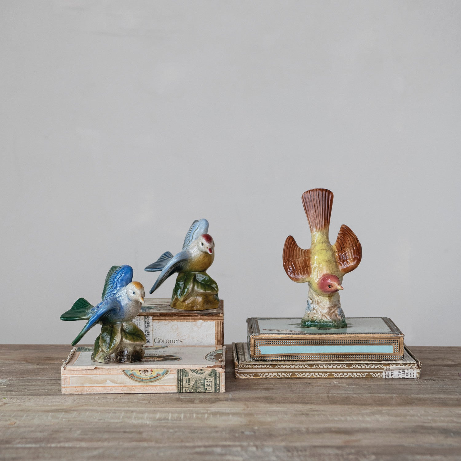 decorative ceramic bird figures arranged on books on a wooden table