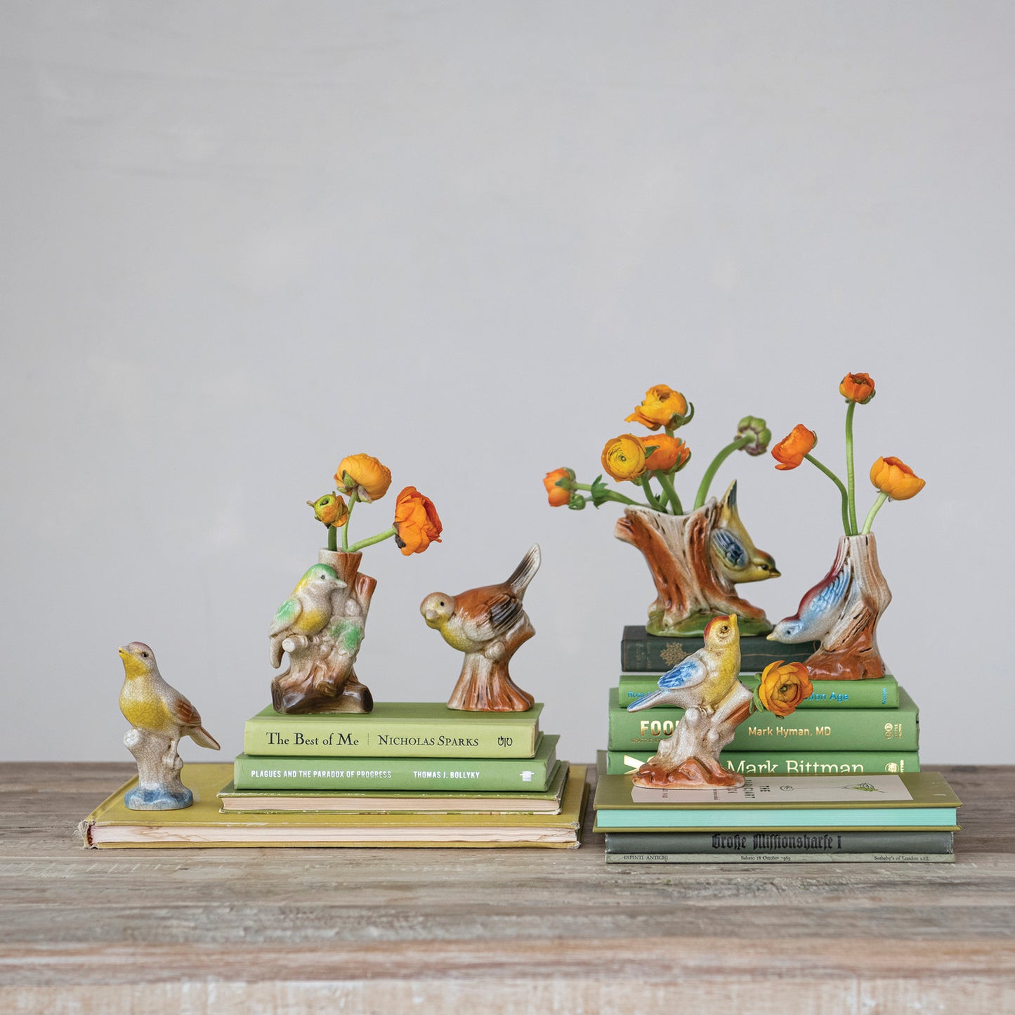 six bird on tree trunk vases with orange flowers in them set on stacks of books