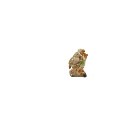 ceramic vase shaped like green bird sitting on a tree branch