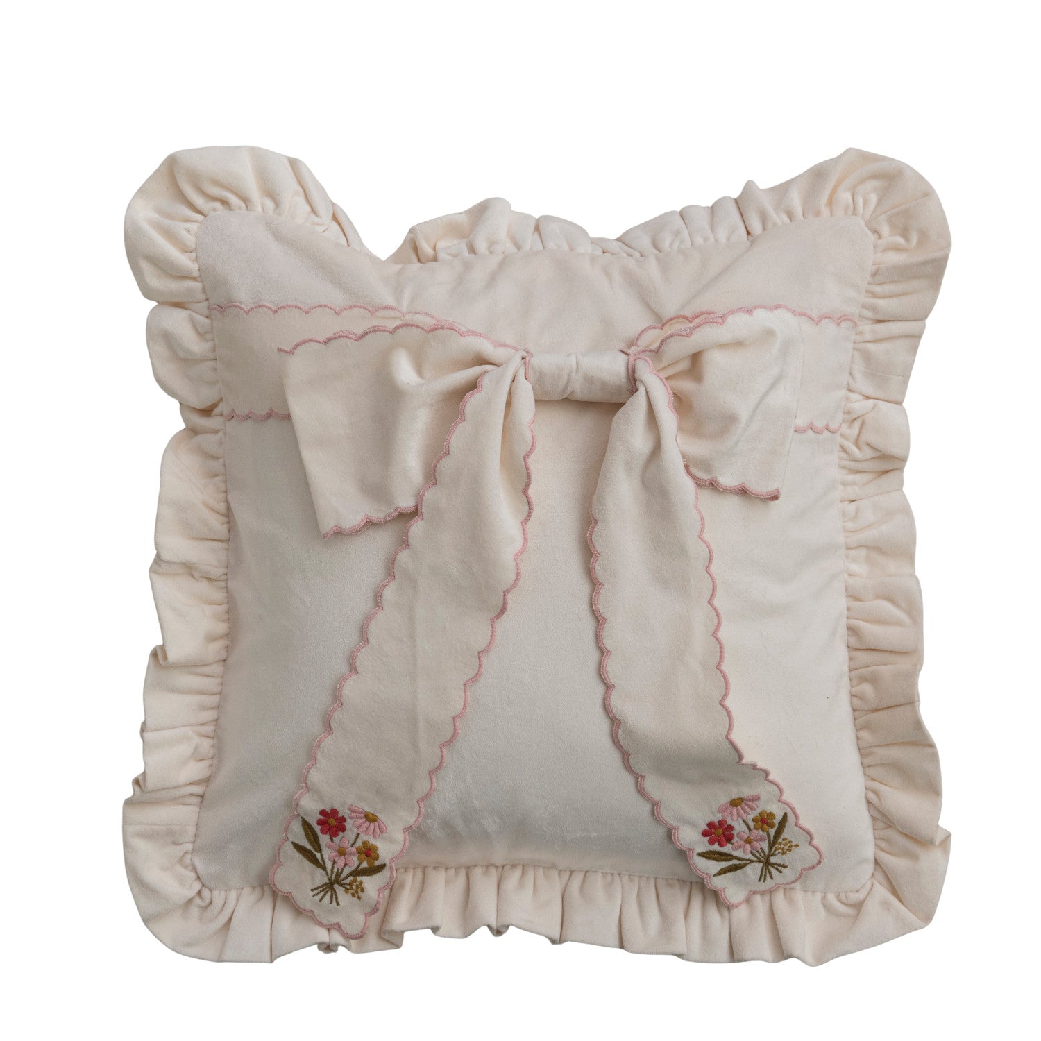 off-white pillow with ruffled trim and oversized bow on, bow has pink scalloped edge and embroidered pink florals on each end