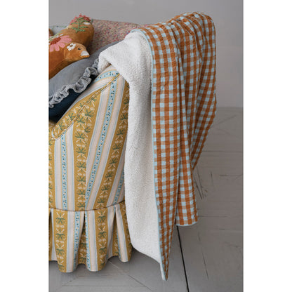 orange and light blue gingham blanket draped over a yellow floral arm chair