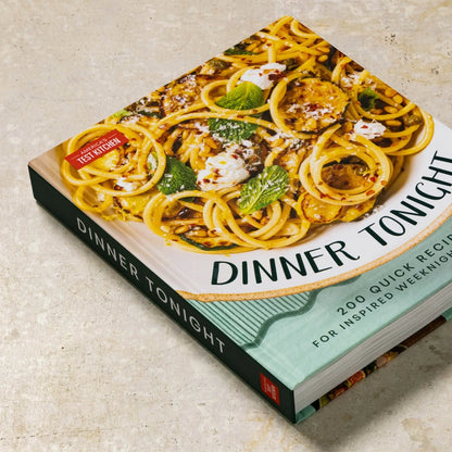 Cookbook titled 'Dinner Tonight' with a pasta dish on the cover, placed on a light surface.