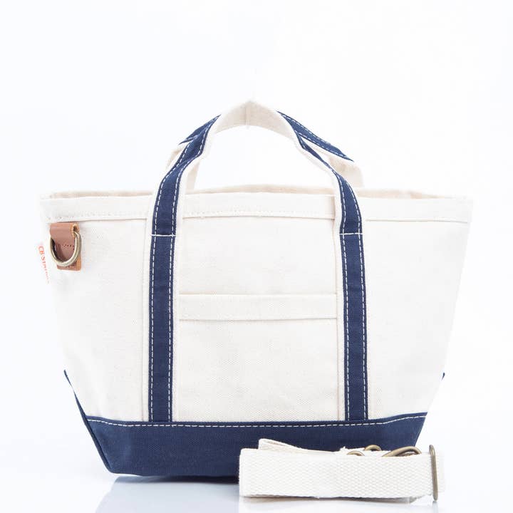 front view of off white tote with navy trim and crossbody strap curled in front of it
