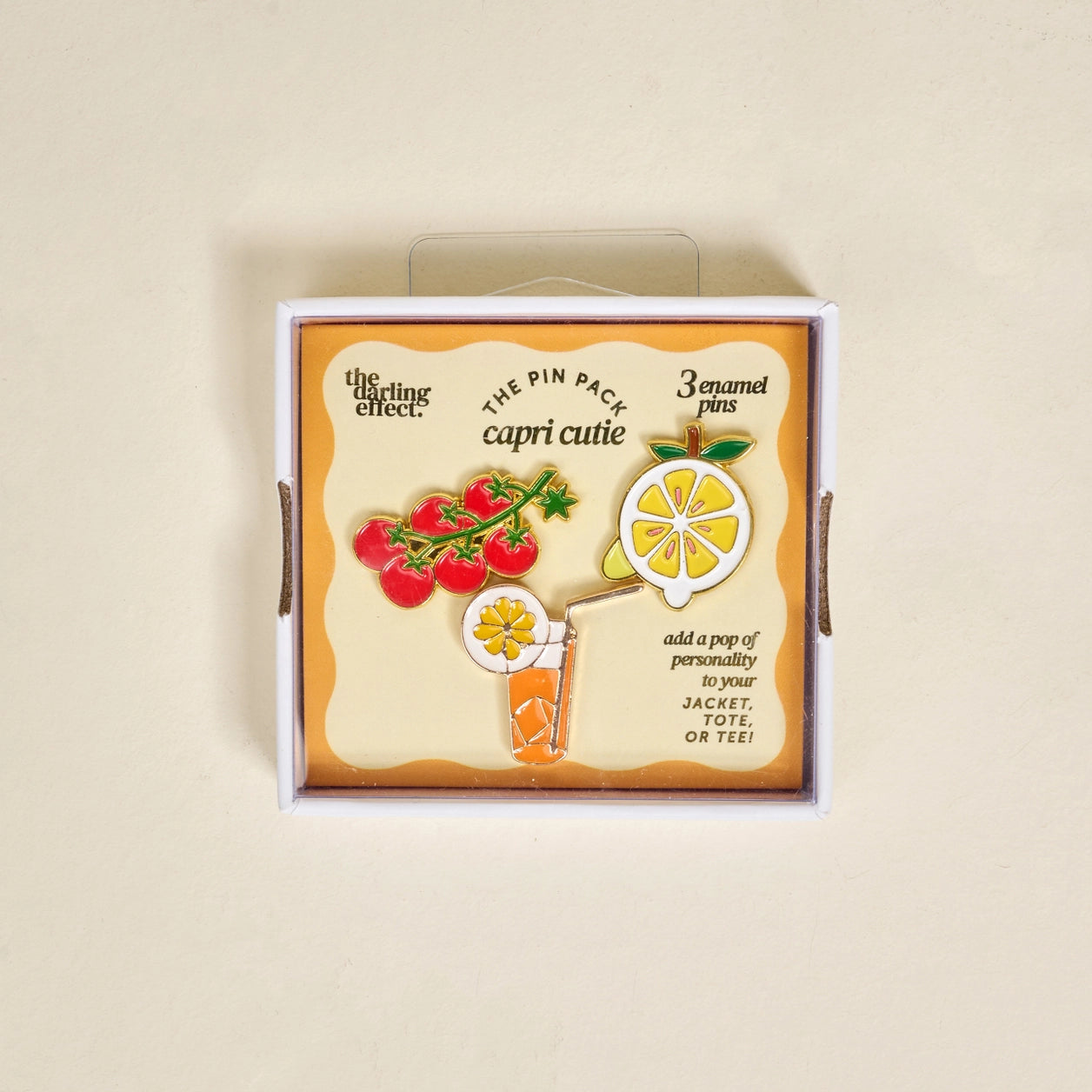 Box of enamel pins with colorful designs in box packaging on a beige background