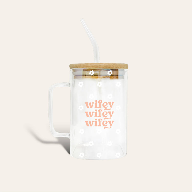 clear glass mug with "wifey wifey wifey" printed in the center surrounded by small white daisies on a light pink background.