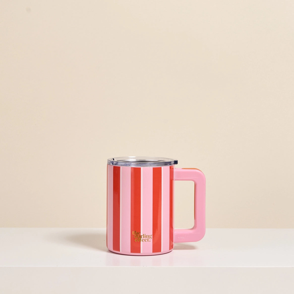 Pink and red striped mug with a handle on a beige background