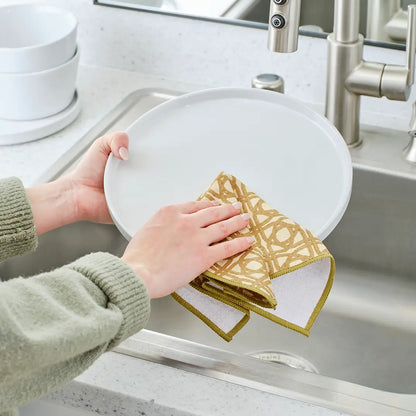 Hand using dish towel with lattice design to clean a plate over the sink.