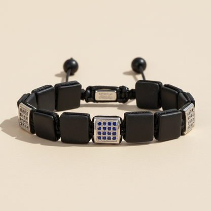 Black bracelet with square beads and a silver clasp on a beige background