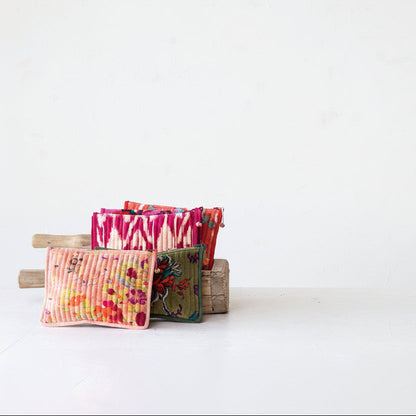 A stack of small colorful fabric pouches displayed on a rustic wooden stand against a plain white background.