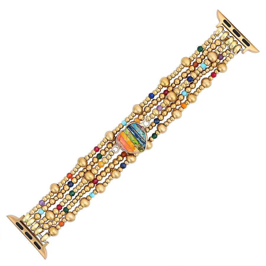 Multicolored beaded watch band with a rainbow-colored heart stone laying flat on a white background