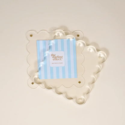 Decorative white frame with a blue and white striped card inside separated to show how to swap out photos
