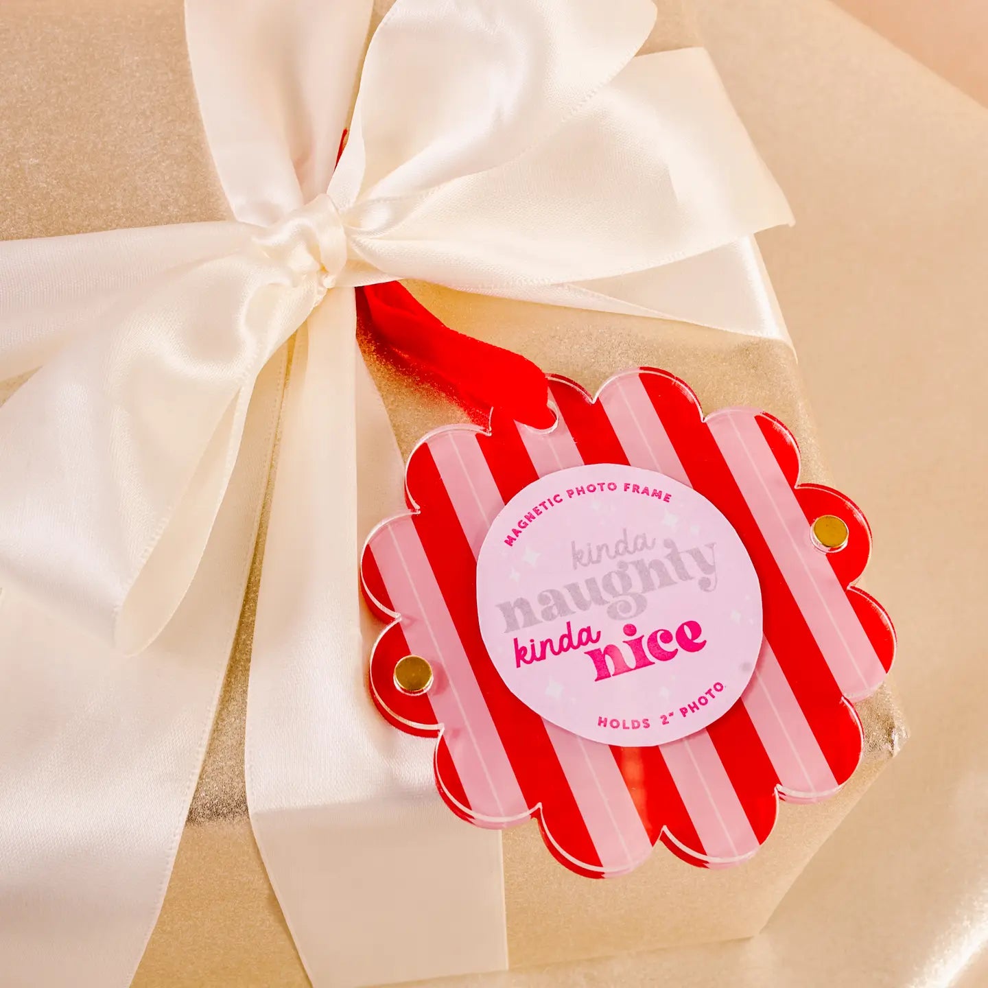 Red and pink striped photo frame tied in an ivory bow on a wrapped gift
